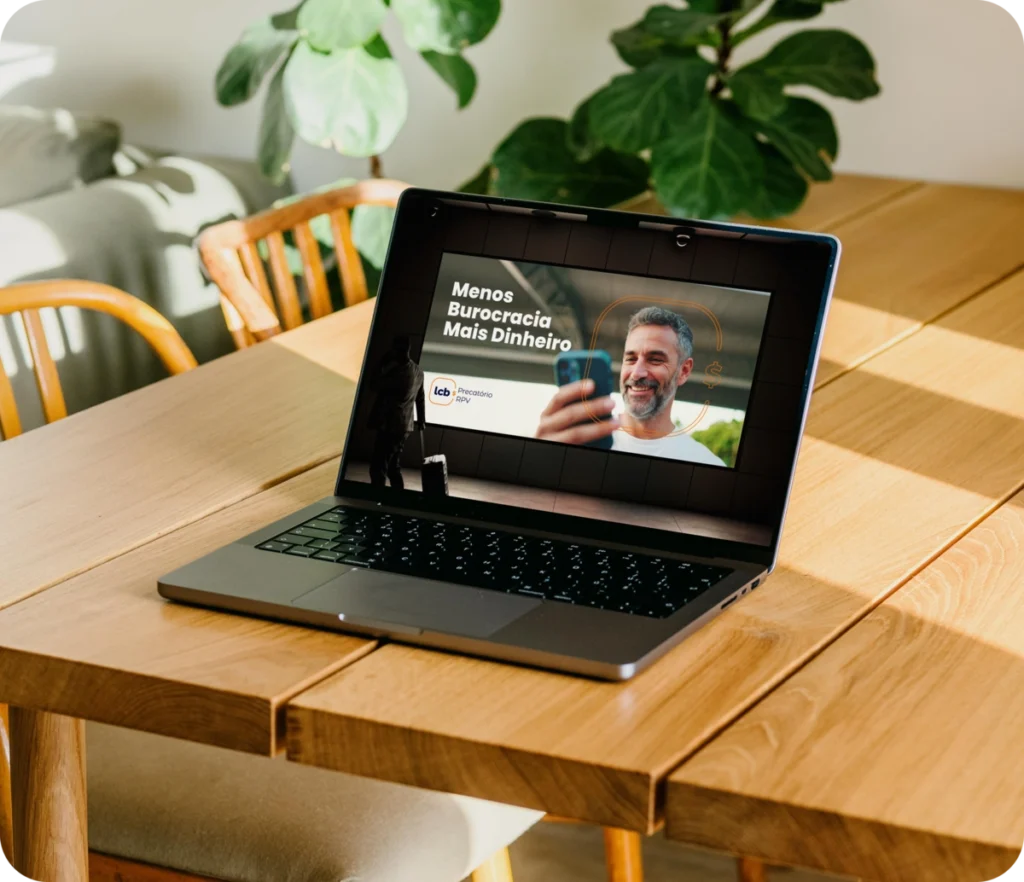 Laptop exibindo vídeo do LCbank sobre "Menos Burocracia Mais Dinheiro